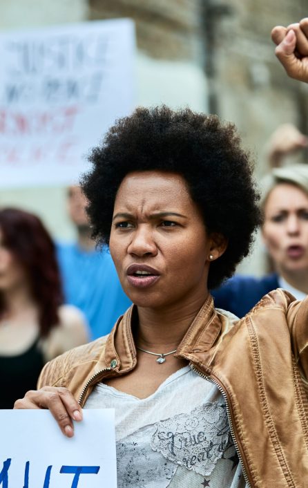 Displeased black woman and crowd of people demonstrating against racism on city streets.